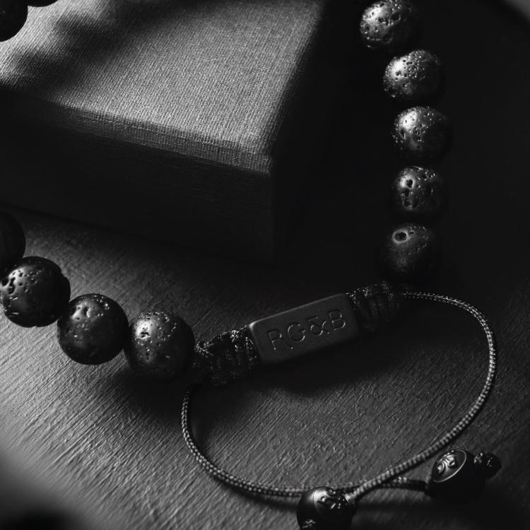 Lava Stone Bead Bracelet - Our Lava Stone Bead Bracelet Features Natural Stones, Waxed Cord and Brushed Black Steel Hardware, Engraved with the Signature RG&B Logo.